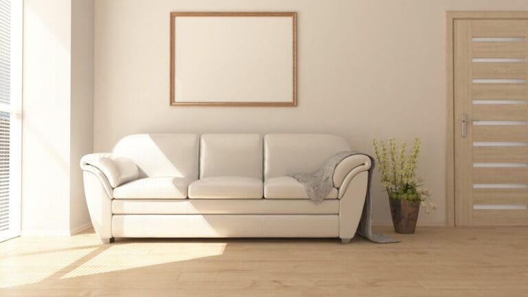 Minimalist living room featuring a cream-colored three-seater sofa centered against a beige wall