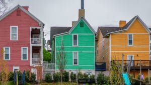 Brightly colored houses in a neighborhood on a cloudy day showcasing diverse exterior paint choices.