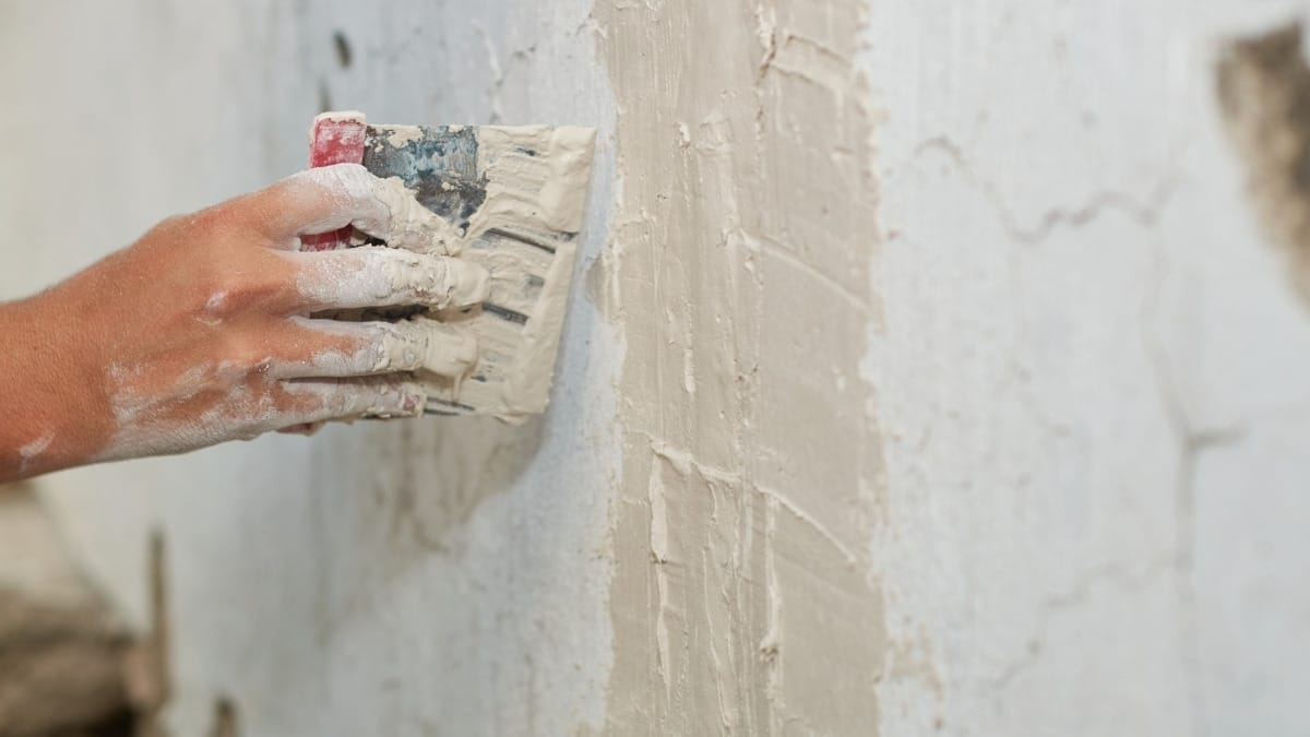 using a putty knife to apply plaster